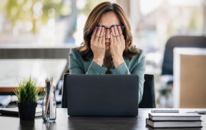 Midlife woman looking stressed while trying to work and feeling frustrated because she cannot lose weight.